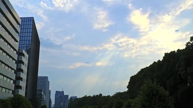 東京港区赤坂の街並み上空を飛ぶ旅客機と光芒のある夏空