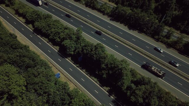 Static top-down drone footage of traffic moving along the M4 motorway near Cardiff, Wales. Cars, vans and lorries travel through multiple motorway lanes while the camera remains fixed overhead, creati