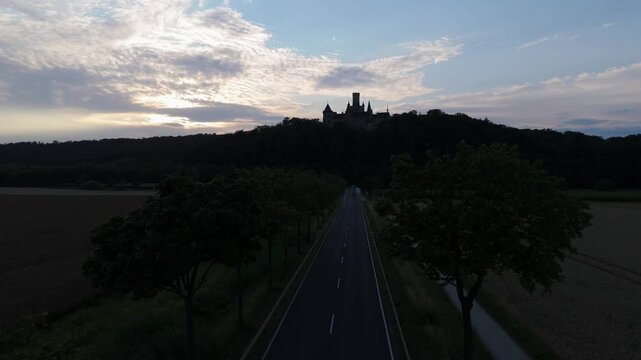 Country road toward Marienburg Castle silhouetted under a sunset sky
