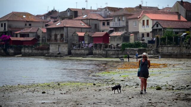 Woman Walking through the Traditional Granite H&oacute;rreos and Coastal Architecture along the Narrow Streets of Combarro in Poio, Galicia, Spain