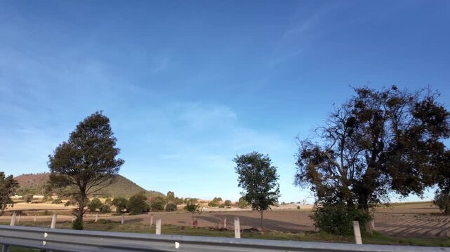 Vista panor&aacute;mica de campos de cultivo en temporada de invierno junto a la carretera con cielo azul.