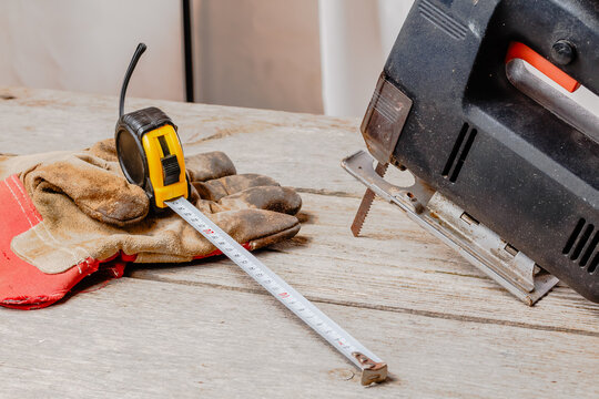 wooden workshop with a jigsaw (hacksaw), tape measure and construction gloves