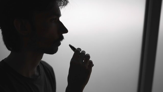 Person Inspects Vapor Production Quality And Flavor Profile Near Window While Reviewing Device . Media