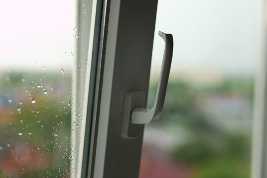 White plastic window handle on a rainy day