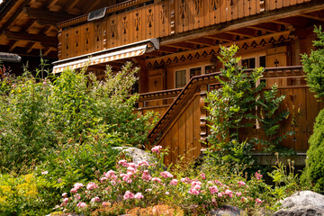 Obraz premium Traditional Swiss chalet wooden house facade close up with blooming summer flower garden in Grindelwald village, alpine Europe
