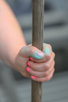 Small hand gripping wooden pole with colorful powder.