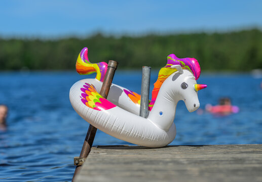 Inflatable unicorn float on dock with swimmers in background.