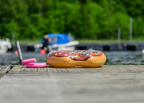 Inflatable donut swim ring waiting on sunny lakeside dock.