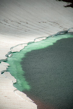 Aerial View of Alpine Crater Lake Edge with Emerald Water Transitioning to Deep Blue Deep