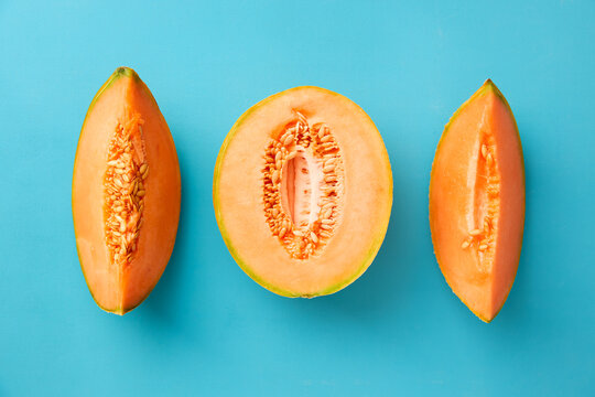Ripe cantaloupe melon cut into slices on blue background