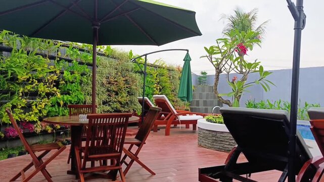 Panning shot of a beautiful backyard patio with wooden furniture and vertical garden