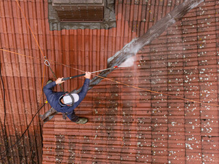 Roof cleaning with pressure washer on historic building during renovation and maintenance of traditional roof tiles. Professional roof cleaning service using pressure washer © Chawran
