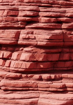 A detailed close-up shot showing the rugged texture and layered strata of a natural red limestone formation with earthy crimson tones, structural, erosion, maroon