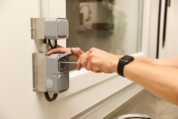 Naklejka premium Electrician installing weatherproof outdoor electrical outlet with screwdriver in modern building