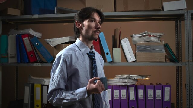 Businessman holding a marker in a dim archive room