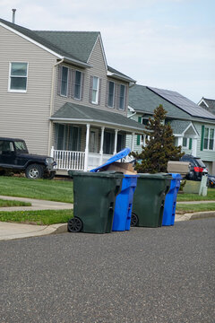 Line of recycling and regular trash cans by the curb on a street