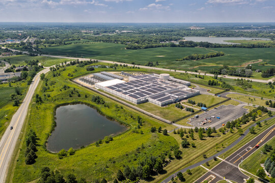 Aerial view of a modern data center facility with solar panels on the roof, cooling units and server buildings