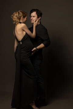 A pregnant slim girl poses with her husband in black outfits