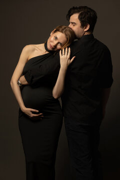 A pregnant slim girl poses with her husband in black outfits