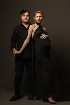 A pregnant slim girl poses with her husband in black outfits