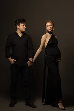 A pregnant slim girl poses with her husband in black outfits