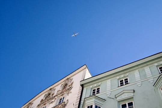Low Angle Photo of Airplane Flying Over Historic Building Facades in Innsbruck Austria for Travel Concept
