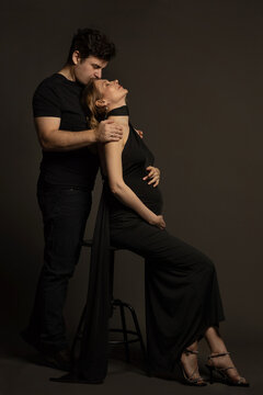 A pregnant slim girl poses with her husband in black outfits