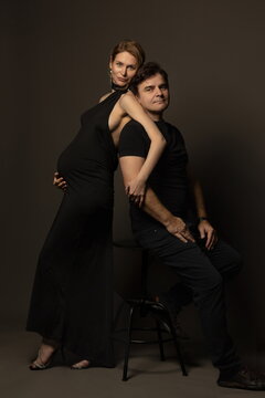 A pregnant slim girl poses with her husband in black outfits