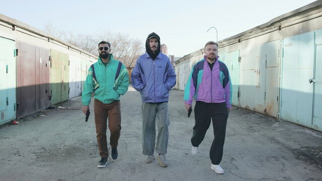 Three Men Dressed In Vivid Wind Resistant Jackets Strut With Assurance And Style In Slow Motion . Media