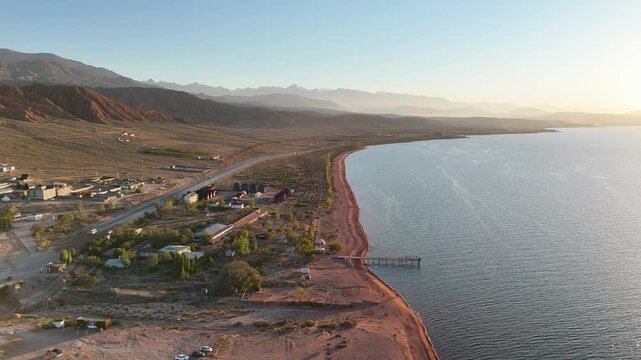 Stunning drone view of Issyk-Kul Lake at sunset, showcasing golden skies