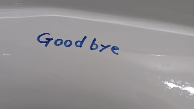 The word "Good bye" written in blue being washed away by water / 青色で書かれた「Good bye」の文字が水に洗い流される様子