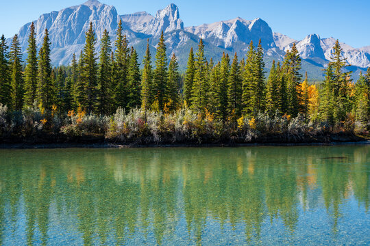 Canadian Rockies autumn landscape. Mount Rundle mountain range and trees reflected on the Bow River. Canmore, Alberta, Canada.