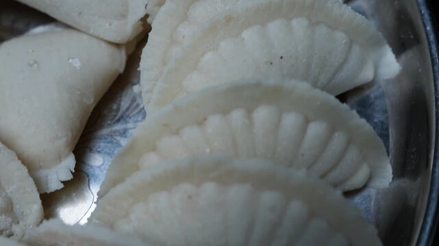 Close up of white steamed dumplings arranged in a metal tray, showing soft folded edges and simple homemade food presentation