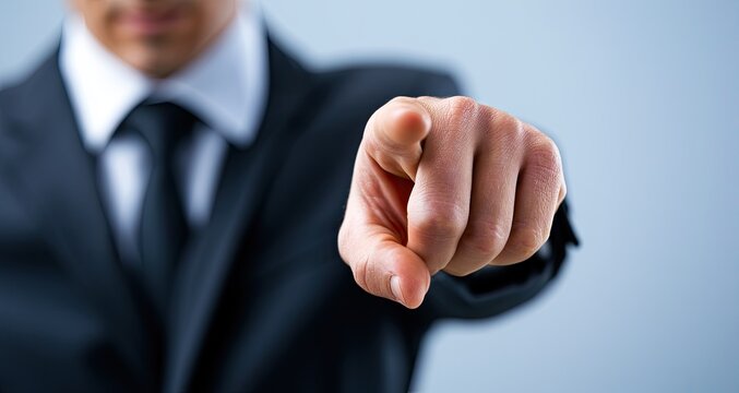 A man in a suit and tie points his index finger directly at the viewer