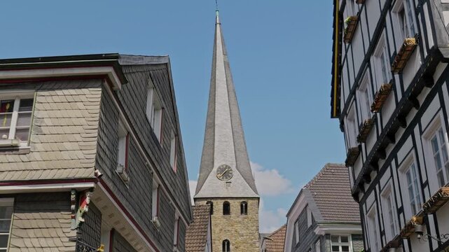 St Georg church twisted spire framed by half timbered and slate houses in Hattingen Germany
