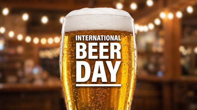 International Beer Day banner with a cold glass of beer with foam in a blurred bar background with bokeh lights.