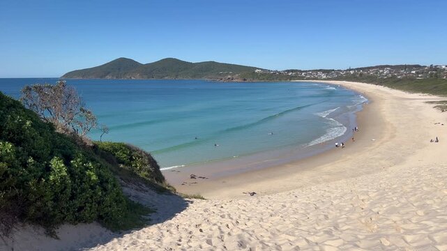 A breathtaking aerial view of the iconic One Mile Sand Dune towering over the pristine coastline of Forster, New South Wales. This massive natural sand hill meets the turqu