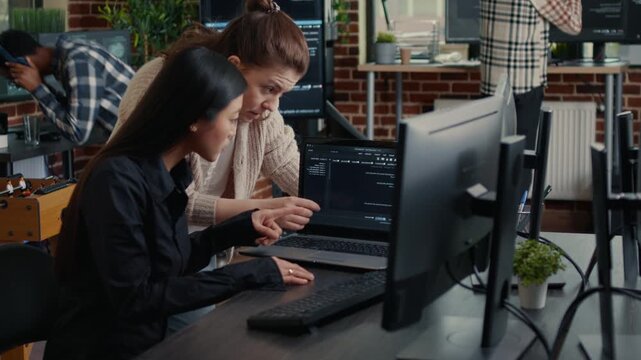 Two software developers analyze compiling issues on shared screens, using collaborative review to identify errors in a development workflow, while building digital application features.