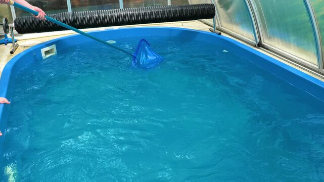 Cleaning swimming pool with telescopic skimmer net.preventive pool care.pool accessories and maintenance instructions. 4k footage