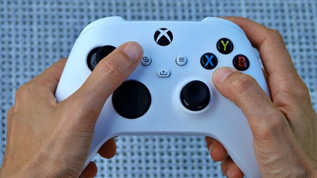 Hands holding a modern white video game controller for immersive digital entertainment, ready to engage in virtual worlds and interactive experiences