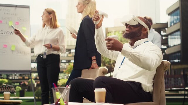 Black business employee with VR glasses uses controllers during outdoor work session, people discuss at whiteboard on terrace, using virtual reality metaverse.