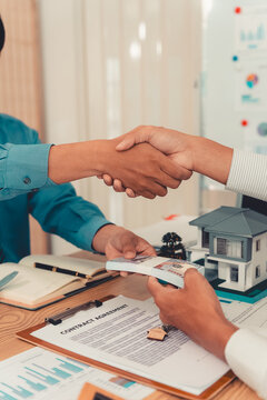 Real estate agent shaking hands with client after signing contract agreement for buying house.