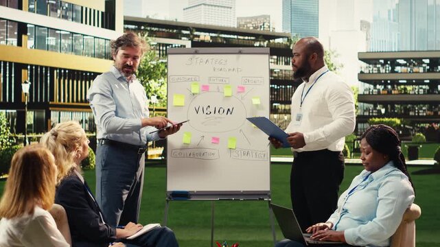 Diverse business people explaining vision implementation with sticky notes, gesturing with open hands during outdoor presentation, informal discussion with coworkers for growth, for business planning.