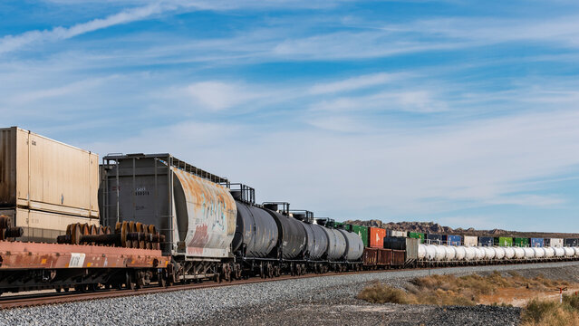 A long Union Pacific Railroad freight train featuring weathered covered hopper cars and tank cars.