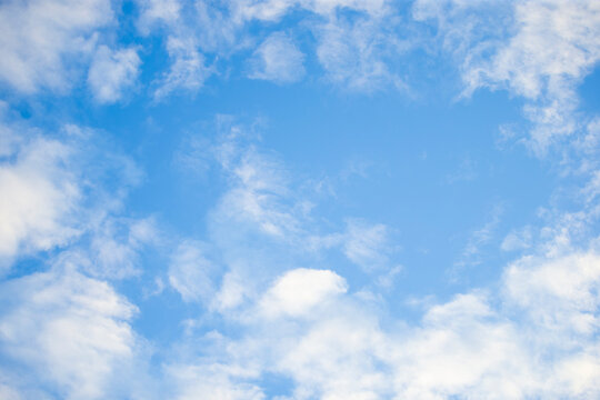 Beautiful bright blue sky with soft white fluffy clouds background.   A stunning and serene background featuring a vibrant blue sky filled with scattered, light fluffy white clouds.
