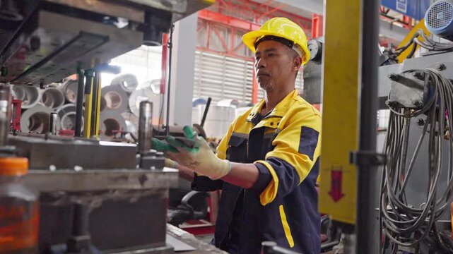 Focused factory worker operating machinery in industrial setting with safety gear and professional attitude