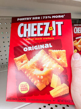 Hand holding a red pantry size box of Cheez-It Original baked snack crackers in a supermarket