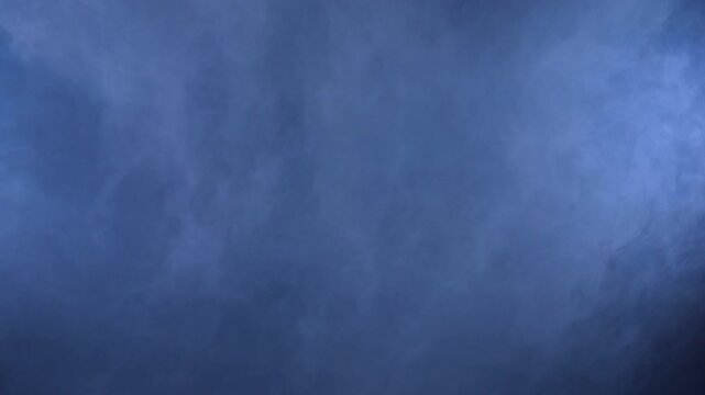 White smoke clouds form over a dark studio backdrop, creating an abstract fog texture for transitions, overlays and visual effects.