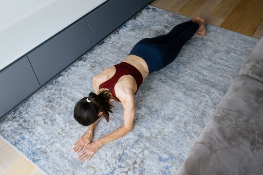 Fit woman performing a plank exercise on a rug at home, focusing on core strength, fitness, and a healthy lifestyle