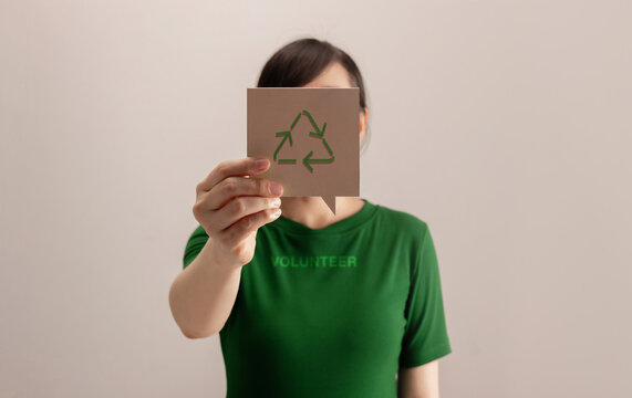Volunteer woman holding a recycling symbol card in front of her